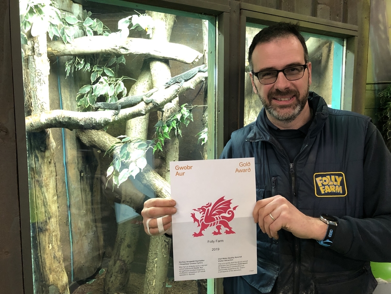 Folly Farm's zoo curator holding the Visit Wales gold award